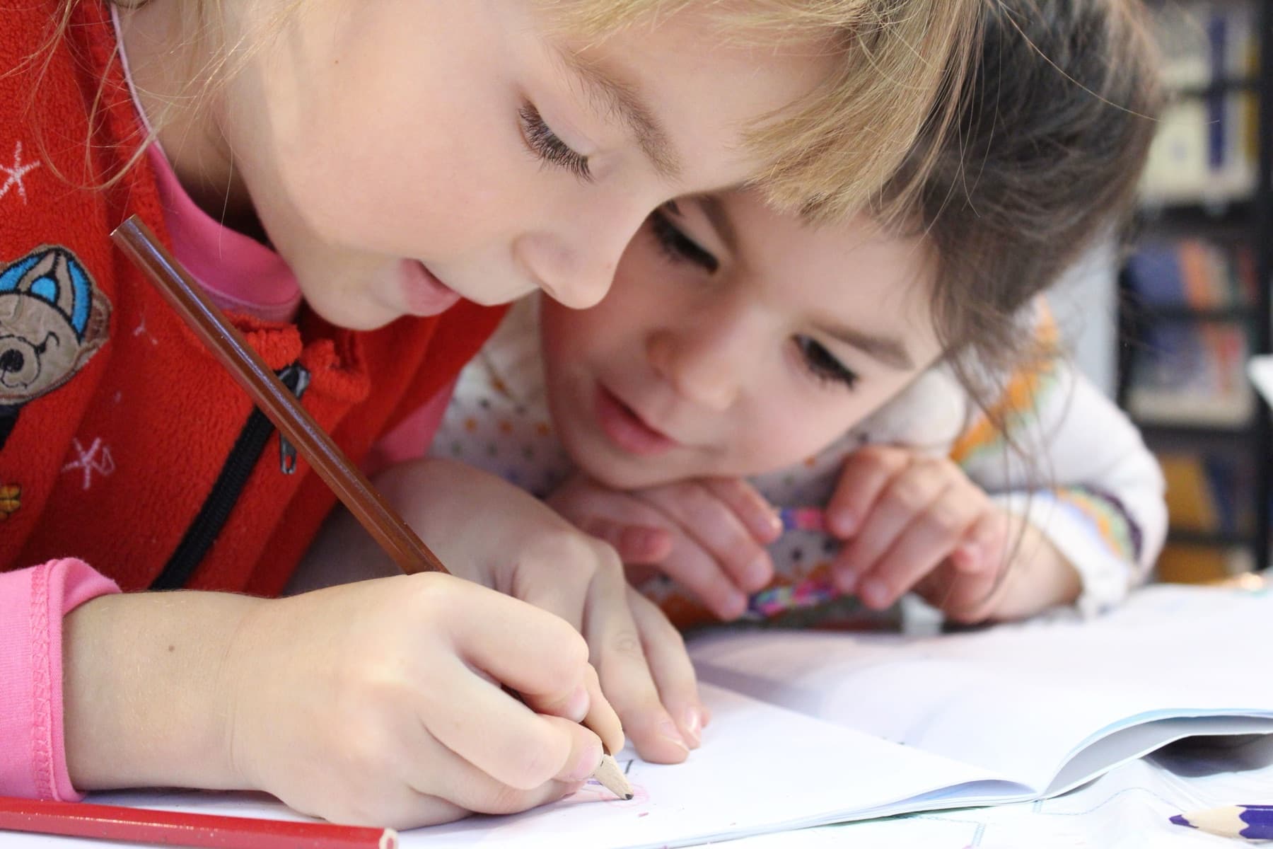 Two children writing side by side at a classroom table